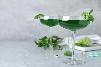Photo of Delicious mint liqueur with green leaves on light grey marble table. Space for text