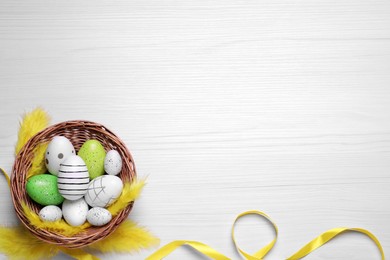 Photo of Flat lay composition with festively decorated Easter eggs on white wooden background. Space for text