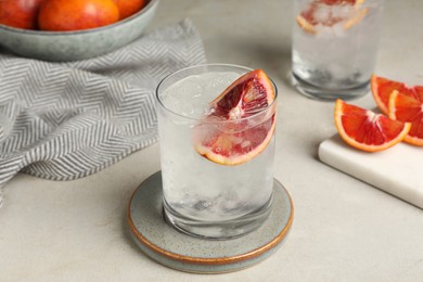 Delicious refreshing drink with sicilian orange and ice cubes on light table