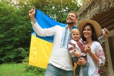 Happy family in national clothes with flag of Ukraine outdoors