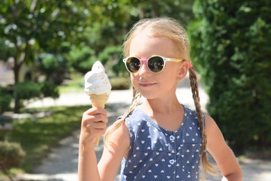 Adorable little girl with delicious ice cream outdoors on sunny summer day