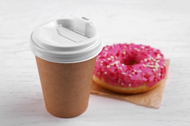 Photo of Tasty frosted donut and hot drink on white wooden table