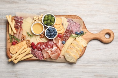 Tasty parmesan cheese and other different appetizers on white wooden table, top view