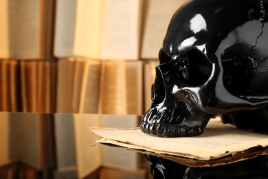 Photo of Back human skull and old book on mirror table, closeup. Space for text