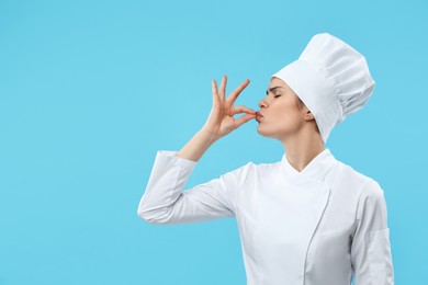 Photo of Female chef showing perfect sign on light blue background. Space for text