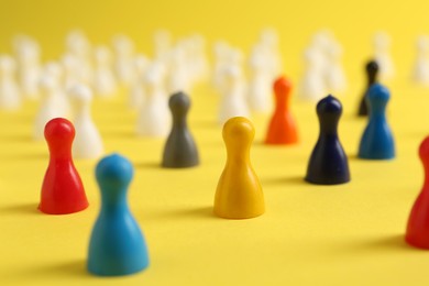 Colorful pawns on yellow background, closeup. Social inclusion concept