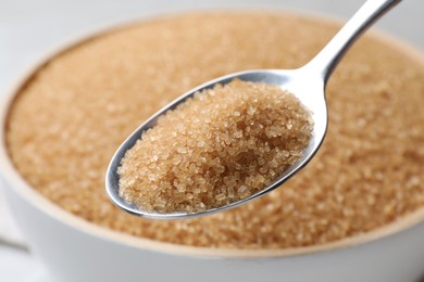 Photo of Spoon with brown sugar over bowl, closeup
