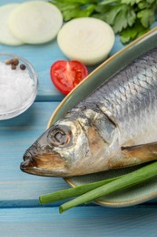 Photo of Delicious salted herring and ingredients on light blue wooden table, closeup