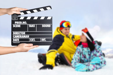 Assistant holding clapperboard and people on snowy hill, closeup. Cinema production 