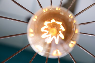 Photo of Stylish metallic pendant lamp with Edison light bulb indoors, bottom view