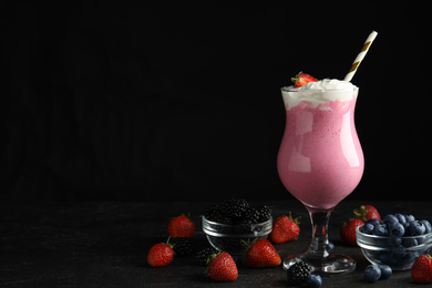 Tasty milk shake with whipped cream and fresh berries on black slate table. Space for text