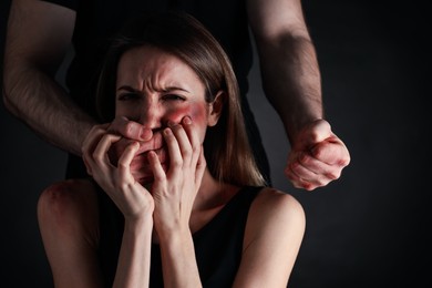 Photo of Man abusing scared woman on black background. Domestic violence