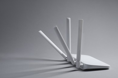 Photo of New stylish Wi-Fi router on grey background. Space for text