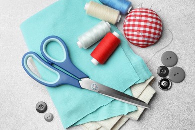 Photo of Flat lay composition with scissors, spools of threads and sewing tools on light background