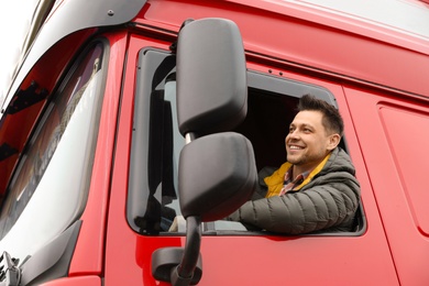 Portrait of happy driver in cab of modern truck