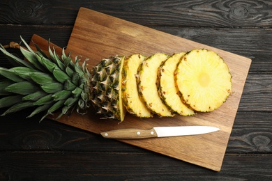 Photo of Tasty cut pineapple on black wooden table, flat lay
