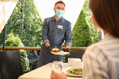 Waiter serving food to customer in restaurant. Catering during coronavirus quarantine