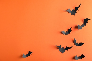 Paper bats on orange background, flat lay with space for text. Halloween decor