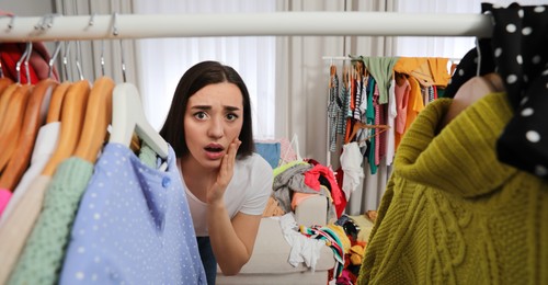 Young woman with lots of clothes in room, banner design. Fast fashion