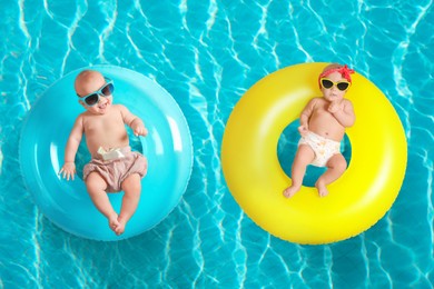 Cute little babies with inflatable rings in swimming pool, top view