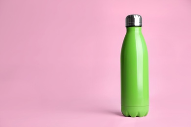 Stylish thermo bottle on pink background, space for text