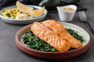 Tasty salmon with spinach on grey table