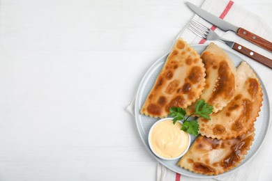Delicious fried chebureki with sauce served on white table, top view. Space for text