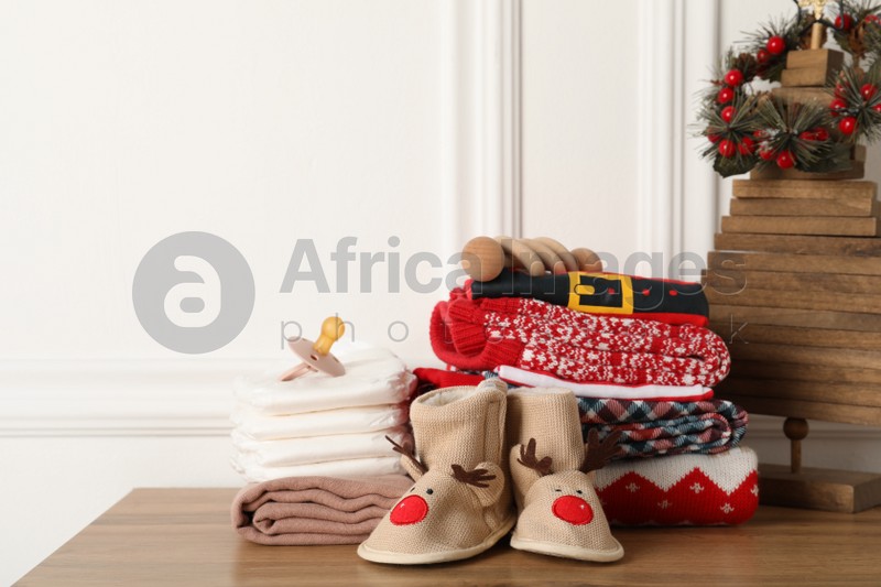 Photo of Baby clothes, accessories and Christmas decor on wooden table