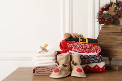 Baby clothes, accessories and Christmas decor on wooden table
