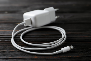 White charging cable and adapter on black wooden table