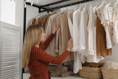 Photo of Young woman choosing outfit in dressing room