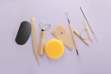 Photo of Set of clay modeling tools on pale violet background, flat lay