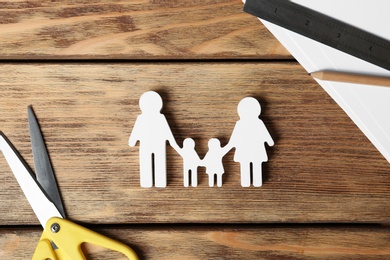 Flat lay composition with family figure and scissors on wooden background. Life insurance concept
