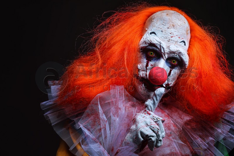 Photo of Terrifying clown on black background. Halloween party costume