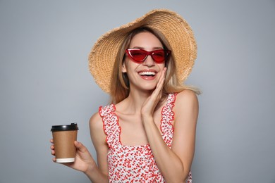 Photo of Beautiful young woman with straw hat, sunglasses and coffee on light grey background. Stylish headdress