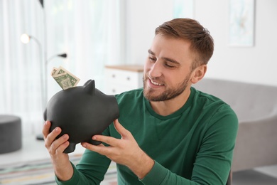 Young man with piggy bank on blurred background