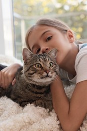 Cute little girl with her cat at home. Childhood pet