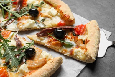 Photo of Tasty pizza with anchovies, arugula and olives on black table, closeup