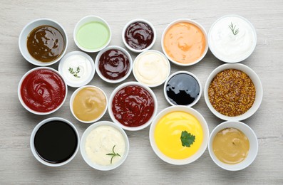 Many different sauces on white wooden table, flat lay