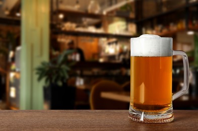 Image of Glass mug with cold tasty beer on wooden table in pub, space for text