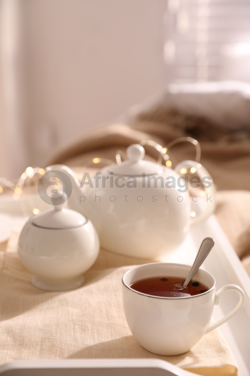 White tray with ceramic tea set on bed