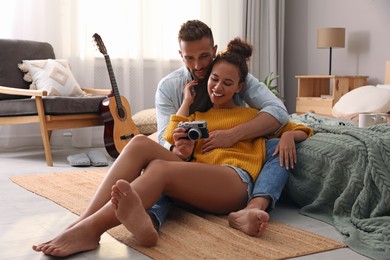Photo of Lovely couple with camera on floor in bedroom