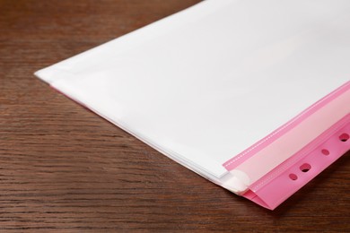 Photo of File folder with punched pockets on wooden table, closeup. Space for text