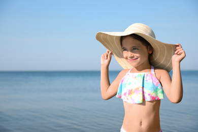Cute little child with straw hat on sunny day. Beach holiday