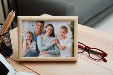 Framed family photo near laptop on wooden table in office