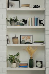 Photo of Cat shaped bookends with books and different decor on shelves indoors. Interior design