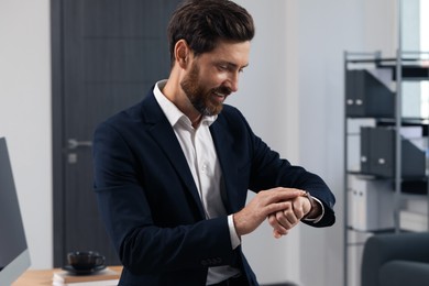 Bearded man looking at wristwatch in office