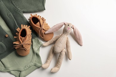 Baby clothes, shoes and toy bunny on white background, flat lay. Space for text