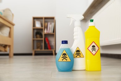 Photo of Bottles of toxic household chemicals with warning signs in room, space for text