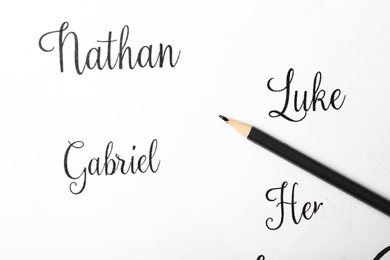 Ordinary pencil and different baby names written on paper, top view